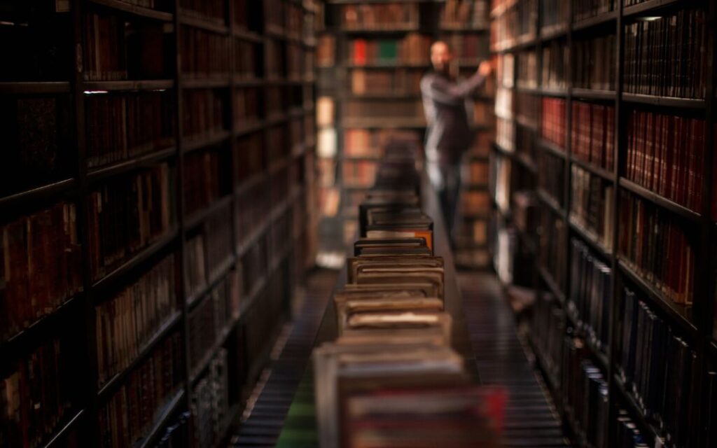 Library with ancient leatherbound books and a shadowy figure illustrates Dark Academic Decor