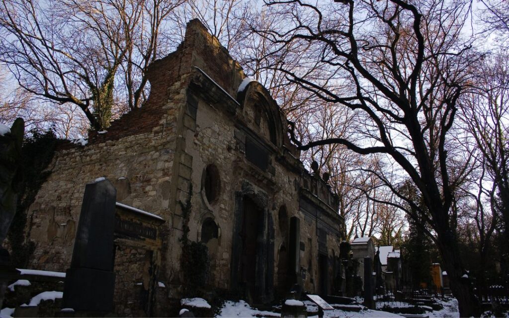 stone crypt in a graveyard with spooky trees and snow illustrates dark academia decor