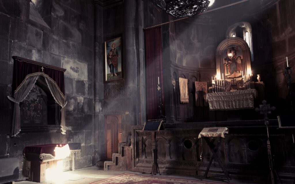 Dark gloomy stone church altar with candles in goth style illustrating dark academia decor