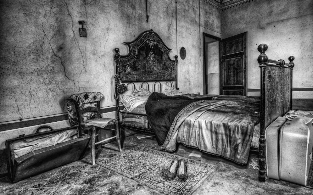 Dark gothic bedroom with velvet bedcoverings and suitcases illustrates Dark Academic Decor