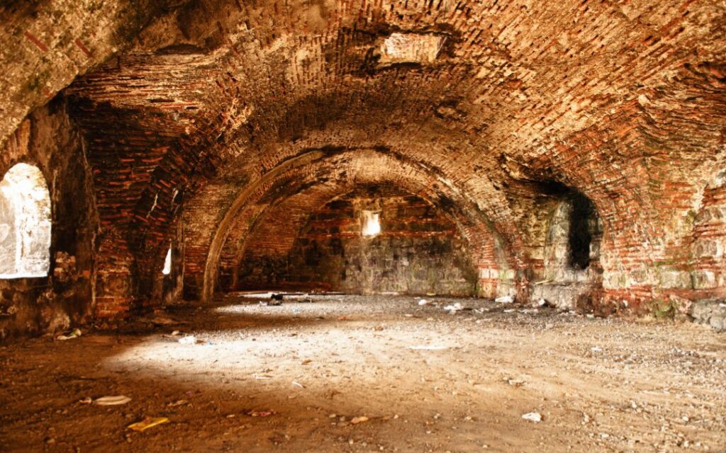 ancient basement with arched brick walls illustrates Dark Academia